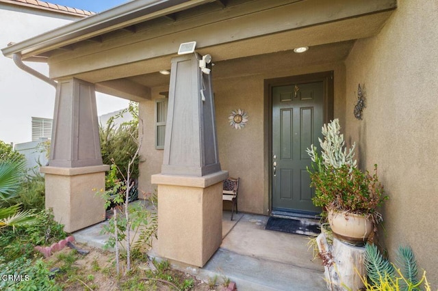 doorway to property with a porch and stucco siding