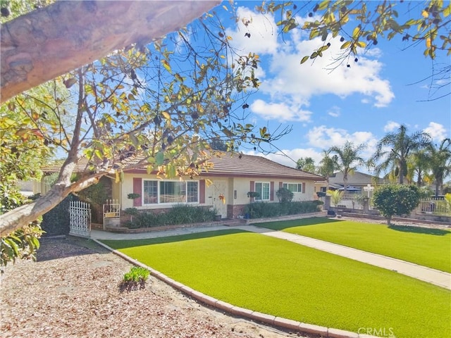 view of front facade with a front yard, fence, a tiled roof, and stucco siding