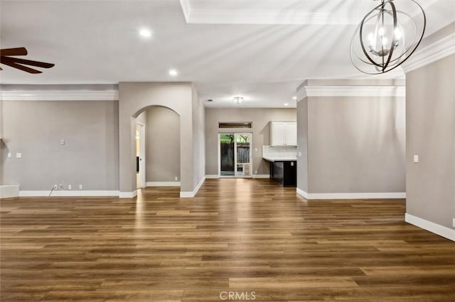 unfurnished living room featuring arched walkways, recessed lighting, ceiling fan with notable chandelier, baseboards, and dark wood-style floors