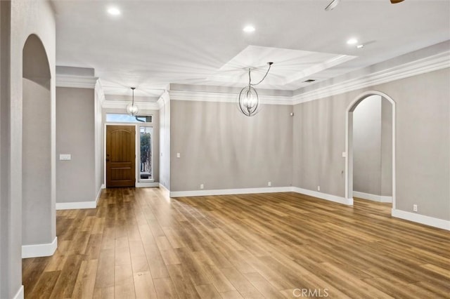 interior space featuring baseboards, arched walkways, ornamental molding, wood finished floors, and a chandelier