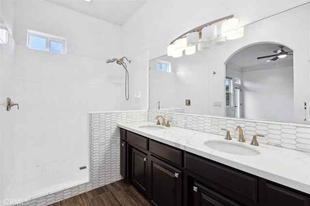 full bathroom with a tile shower, a sink, and wood finished floors