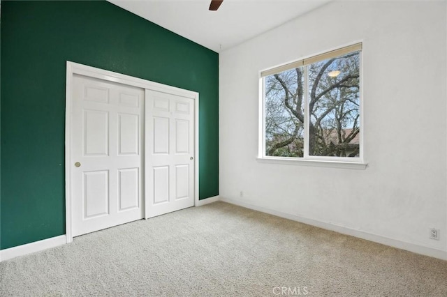 unfurnished bedroom featuring a ceiling fan, a closet, carpet flooring, and baseboards