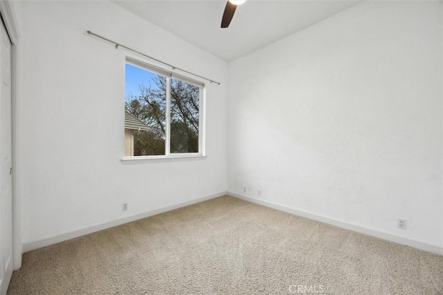 carpeted spare room featuring ceiling fan and baseboards