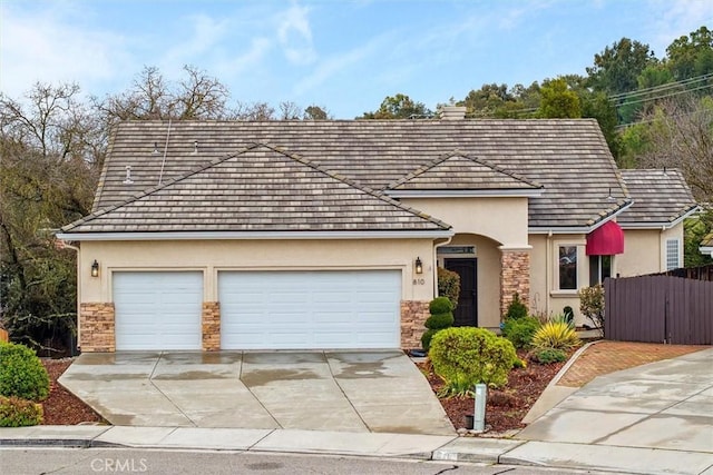 view of front facade featuring a garage, stone siding, concrete driveway, and stucco siding