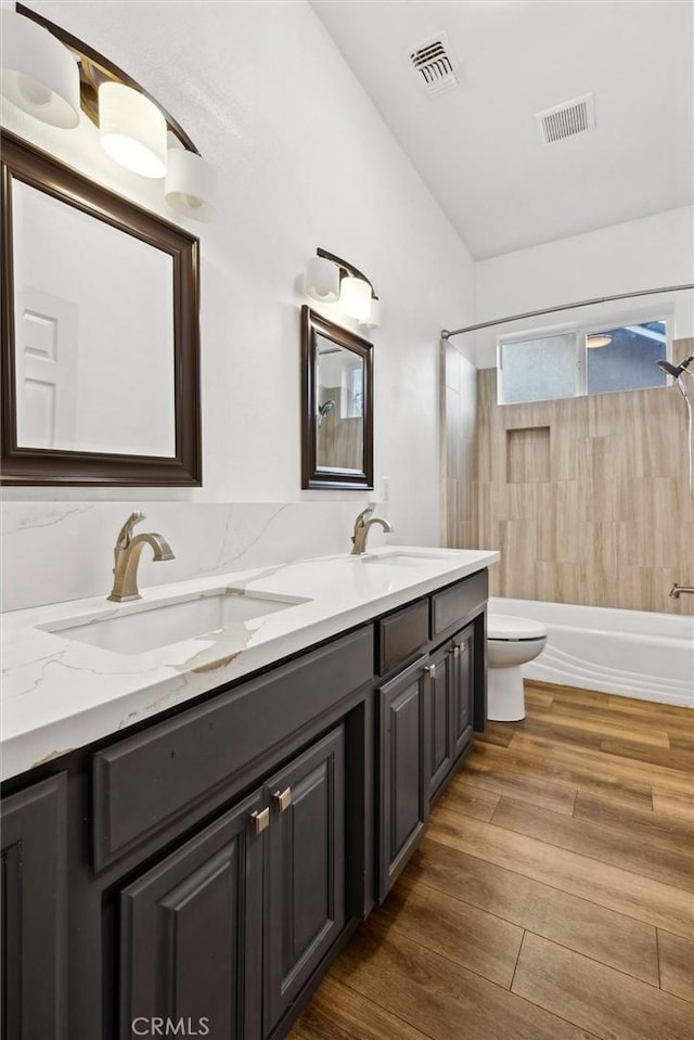 bathroom with toilet, visible vents, a sink, and wood finished floors