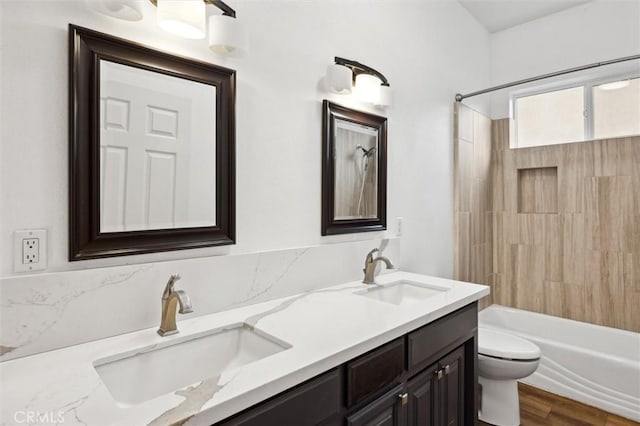 bathroom featuring double vanity, shower / washtub combination, a sink, and toilet