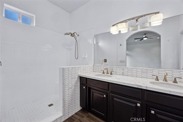 full bath with backsplash, a sink, and a tile shower