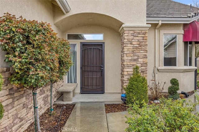 doorway to property featuring stone siding and stucco siding