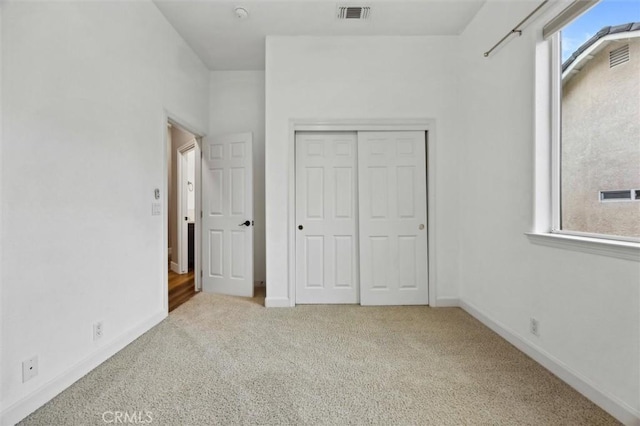 unfurnished bedroom with carpet, a closet, visible vents, and baseboards