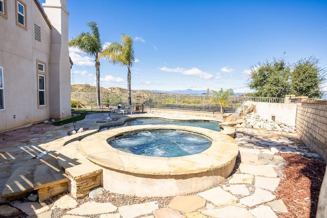 view of pool with a fenced backyard, a mountain view, a patio, and an in ground hot tub