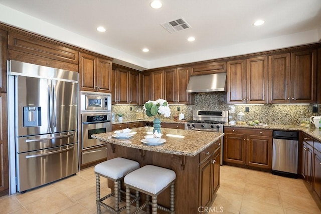 kitchen with visible vents, appliances with stainless steel finishes, ventilation hood, a center island, and a warming drawer