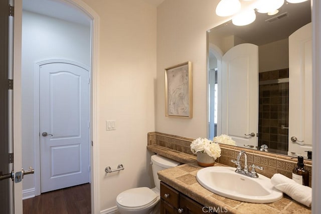 bathroom featuring visible vents, backsplash, toilet, vanity, and wood finished floors