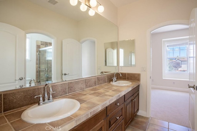 full bathroom featuring double vanity, tile patterned floors, a sink, and a shower stall