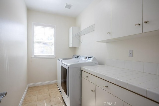 laundry area with washer and clothes dryer, light tile patterned floors, visible vents, cabinet space, and baseboards