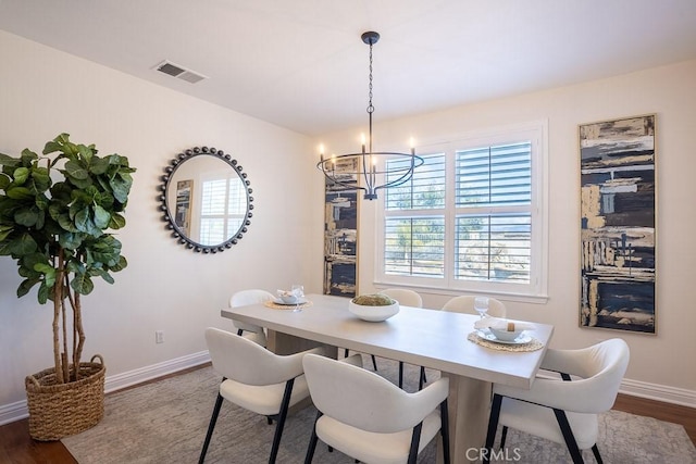 dining room with baseboards, visible vents, a chandelier, and dark wood-style flooring