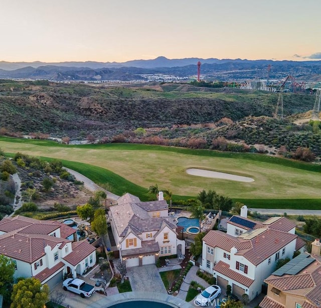 aerial view at dusk featuring a mountain view and golf course view