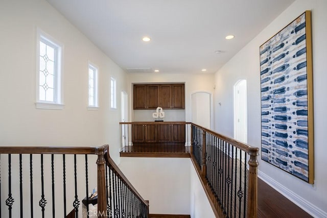 hallway with dark wood-style flooring, recessed lighting, visible vents, an upstairs landing, and baseboards