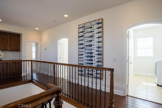 corridor featuring arched walkways, wood finished floors, a healthy amount of sunlight, and recessed lighting