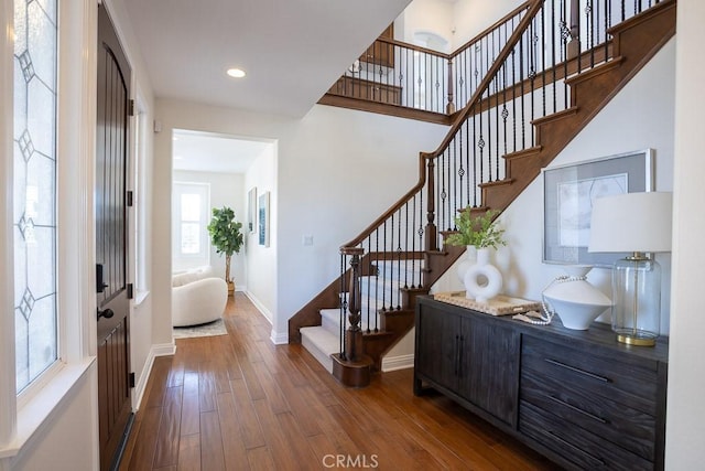 entryway with stairway, baseboards, wood finished floors, and recessed lighting