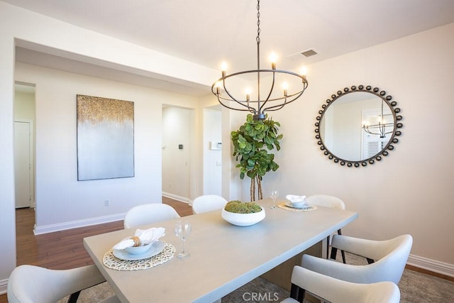 dining room with dark wood-style floors, baseboards, visible vents, and an inviting chandelier