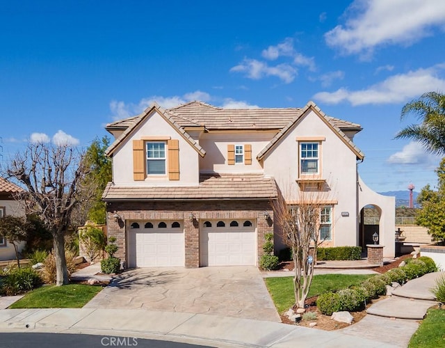 mediterranean / spanish house featuring concrete driveway, a tiled roof, an attached garage, and stucco siding