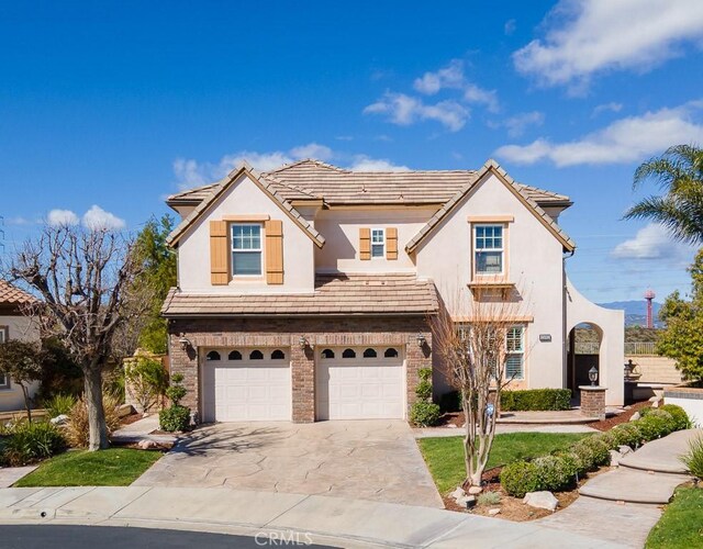 25663 Elmwood Ln, Valencia, CA 91381 - view of front of property with an attached garage, a tile roof, stucco siding, brick siding, and driveway