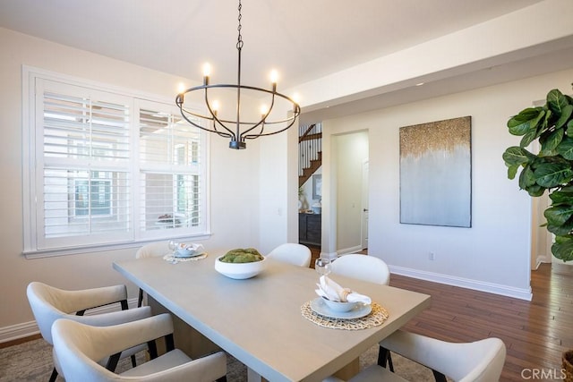 dining space featuring dark wood-style floors, stairway, baseboards, and a notable chandelier