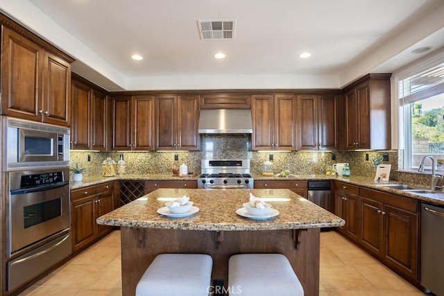 kitchen featuring visible vents, wall chimney exhaust hood, appliances with stainless steel finishes, a sink, and a warming drawer