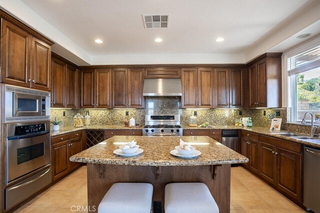 25663 Elmwood Ln, Valencia, CA 91381 - kitchen featuring wall chimney range hood, visible vents, a warming drawer, a sink, and stainless steel appliances