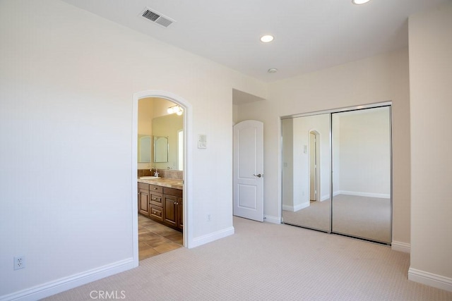 unfurnished bedroom featuring recessed lighting, light colored carpet, a sink, visible vents, and a closet