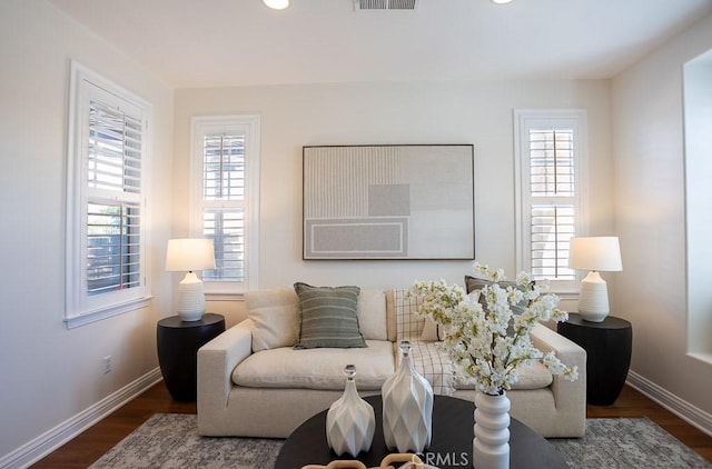 living room featuring visible vents, plenty of natural light, baseboards, and wood finished floors