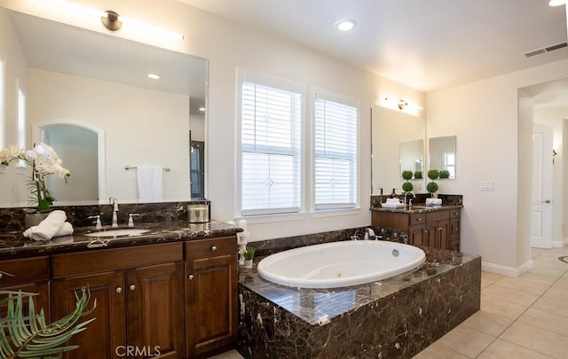 bathroom featuring visible vents, a jetted tub, a sink, tile patterned flooring, and two vanities