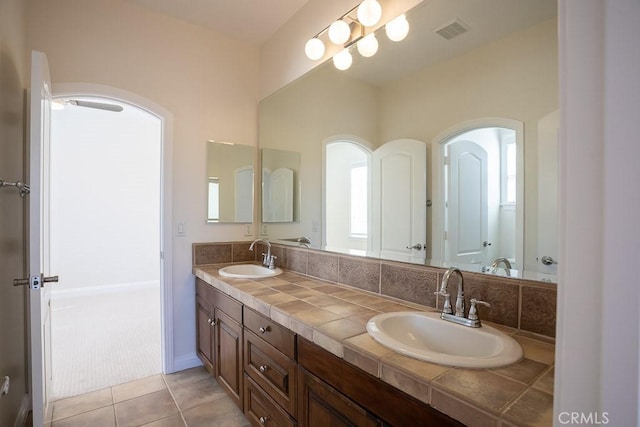 bathroom featuring tile patterned flooring, visible vents, a sink, and double vanity