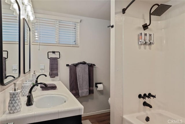 bathroom with double vanity, baseboards, wood finished floors, shower / washtub combination, and a sink