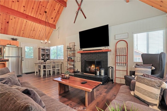 living area featuring beamed ceiling, a brick fireplace, wood finished floors, and wooden ceiling