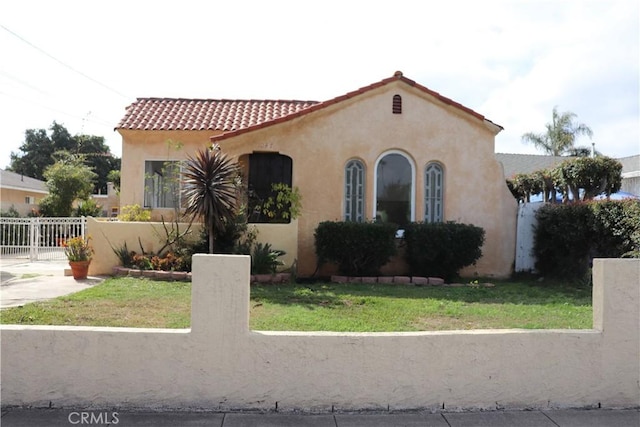 mediterranean / spanish home featuring a tile roof, a gate, fence, and stucco siding