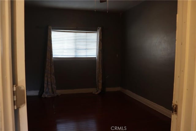 empty room featuring dark wood-type flooring and baseboards