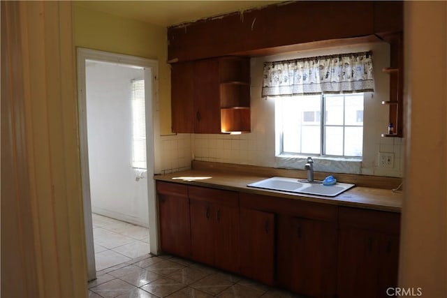 kitchen with light countertops, a sink, backsplash, and light tile patterned floors