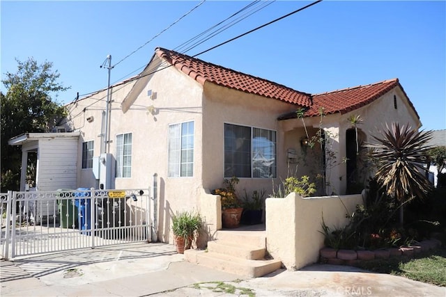 mediterranean / spanish-style home featuring a tiled roof, fence, and stucco siding