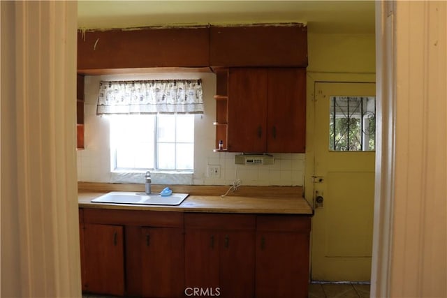 kitchen featuring light countertops, a sink, backsplash, and open shelves