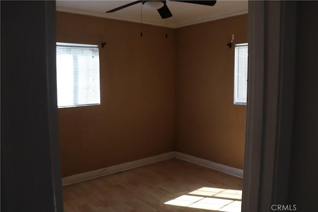 spare room with light wood-style floors, baseboards, ornamental molding, and ceiling fan