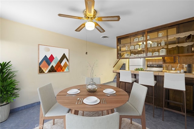 tiled dining space featuring visible vents, ceiling fan, and baseboards