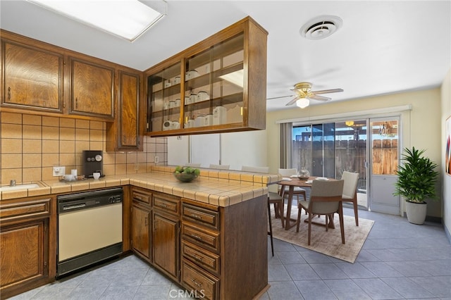 kitchen featuring white dishwasher, visible vents, backsplash, and light tile patterned flooring