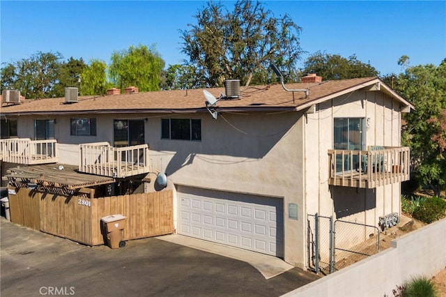 view of front of property with driveway, a chimney, an attached garage, fence, and cooling unit