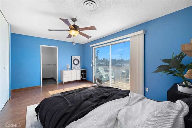 bedroom with visible vents, ceiling fan, wood finished floors, access to outside, and a textured ceiling