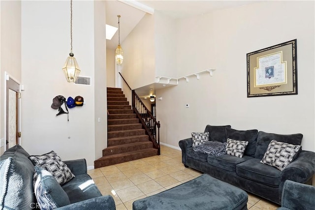 living area featuring light tile patterned floors, stairway, high vaulted ceiling, and visible vents