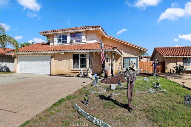 mediterranean / spanish-style house featuring stucco siding, a tile roof, fence, concrete driveway, and an attached garage