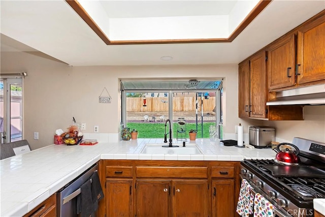 kitchen featuring under cabinet range hood, stainless steel appliances, brown cabinetry, and a sink