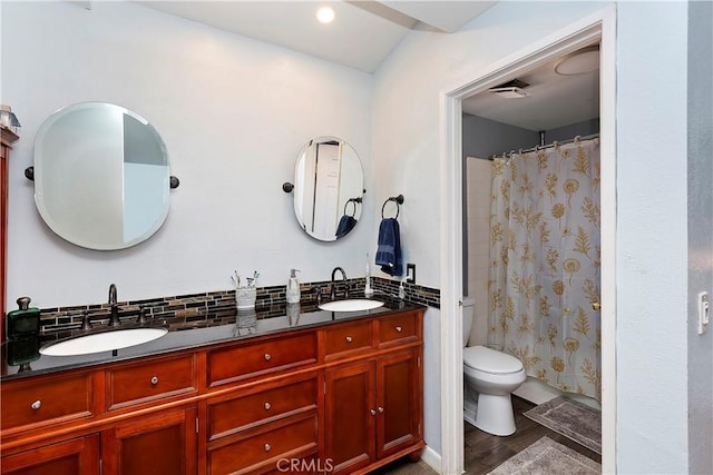 full bathroom with double vanity, toilet, tasteful backsplash, and a sink