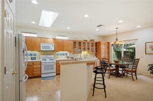 kitchen featuring a center island, a breakfast bar area, tile counters, glass insert cabinets, and white appliances